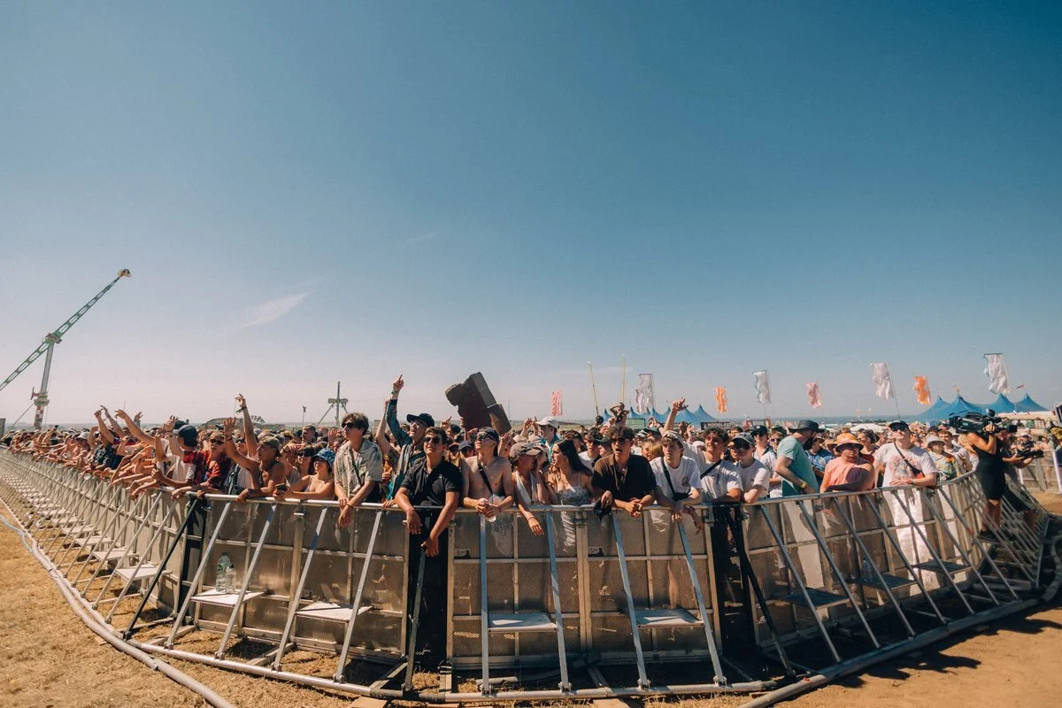 Front-of-stage crowd barrier at an outdoor festival on a clear day
