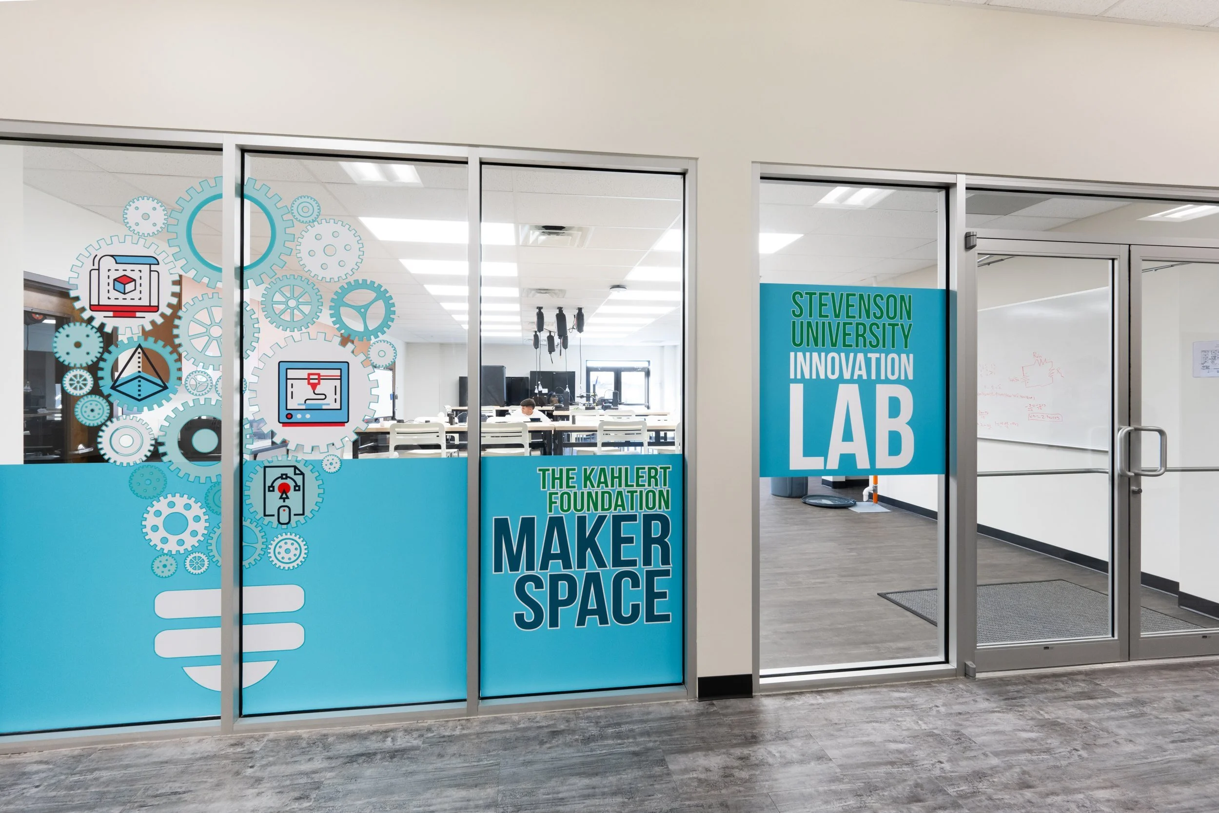 Glass entrances to the Kahlert Foundation Maker Space and the Stevenson University Innovation Lab, with teal graphics of gears