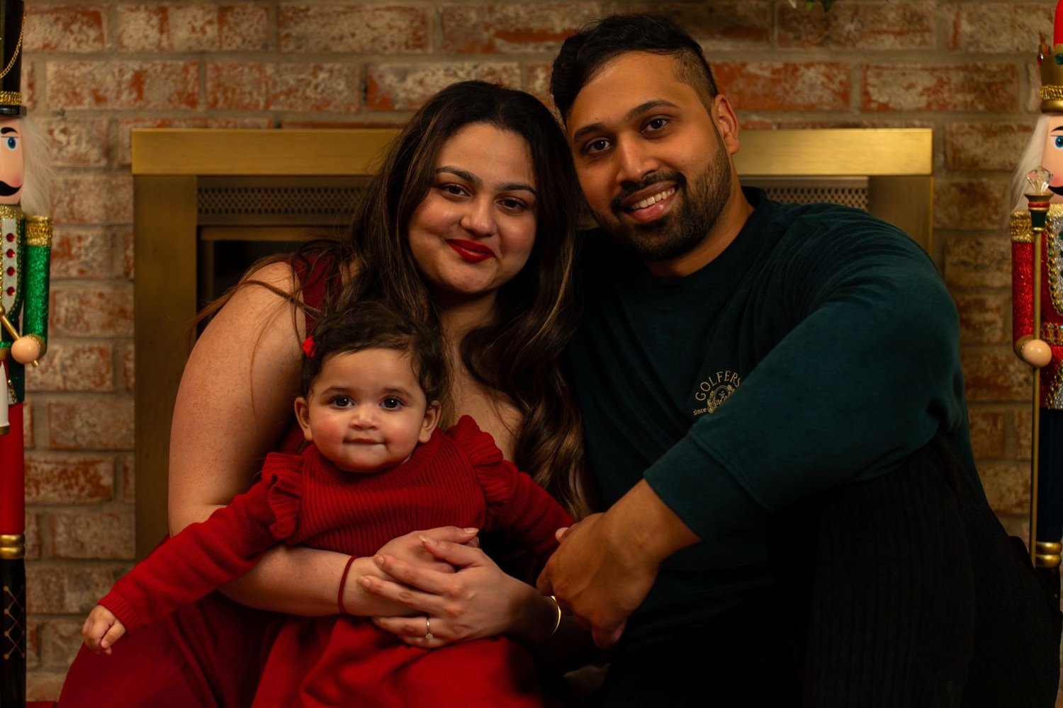 Family of three by a fireplace decorated for the holidays