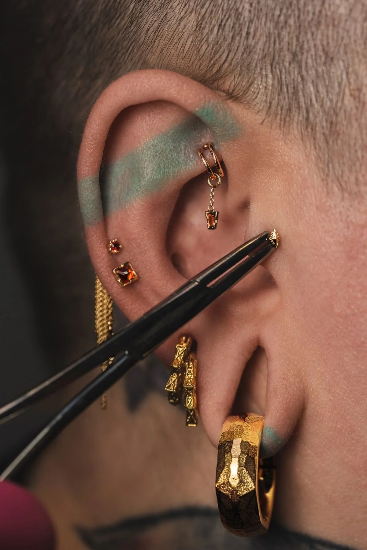 Jeweler placing a piercing with forceps during a studio campaign shoot