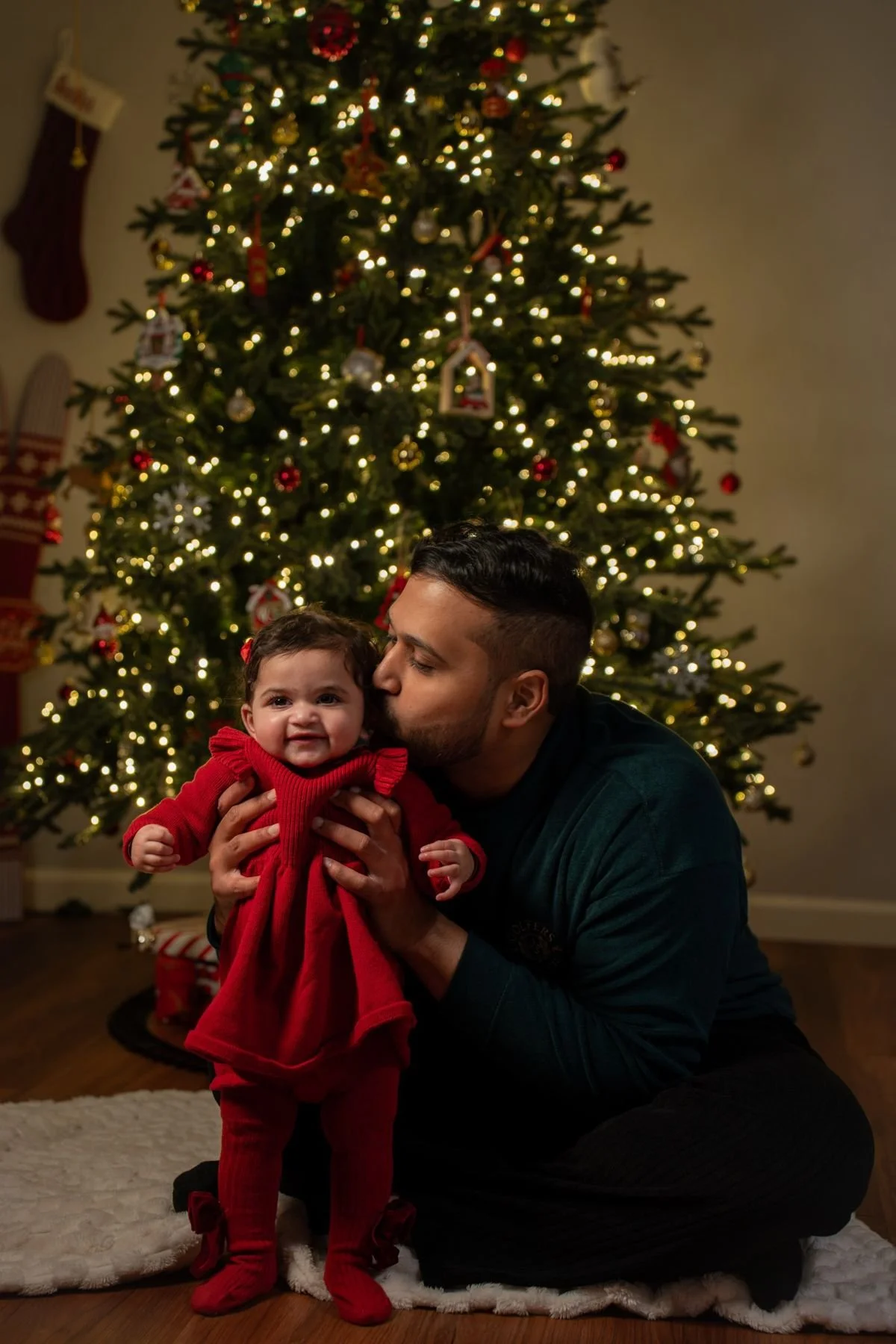 Father holding his daughter in front of a Christmas tree