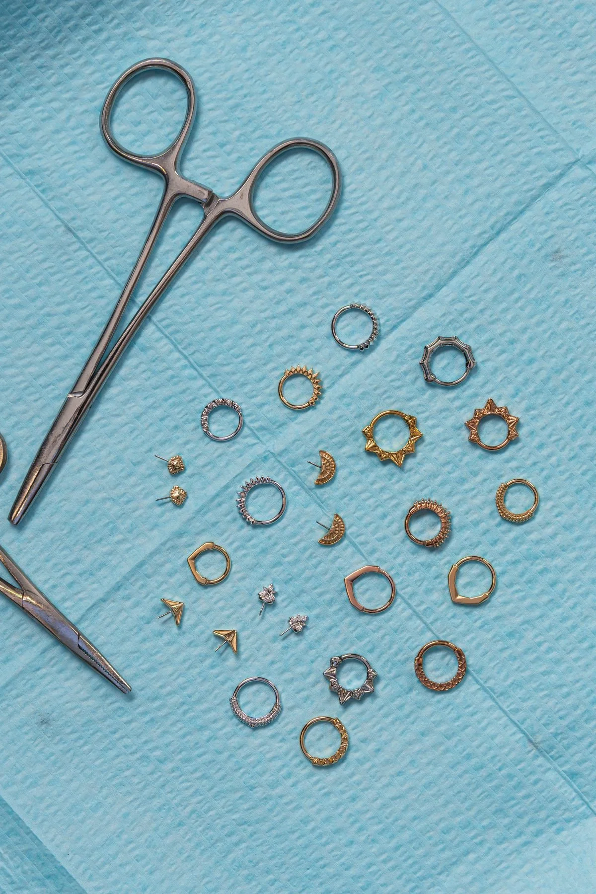 Jewelry pieces and tools laid out on a blue surgical drape