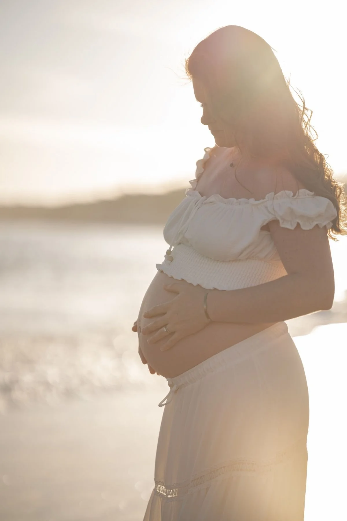 Expecting mother in a flowing dress on the beach