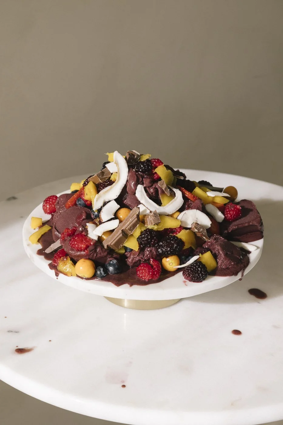 Açaídessert på kakefat med bær, mango, sjokolade og kokos