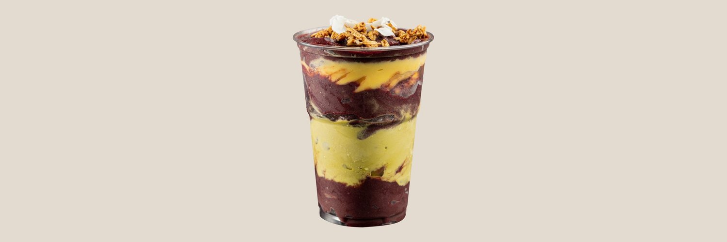 Açaí lag på lag i høyt plastbeger med pistasj, mango, granola og kokos