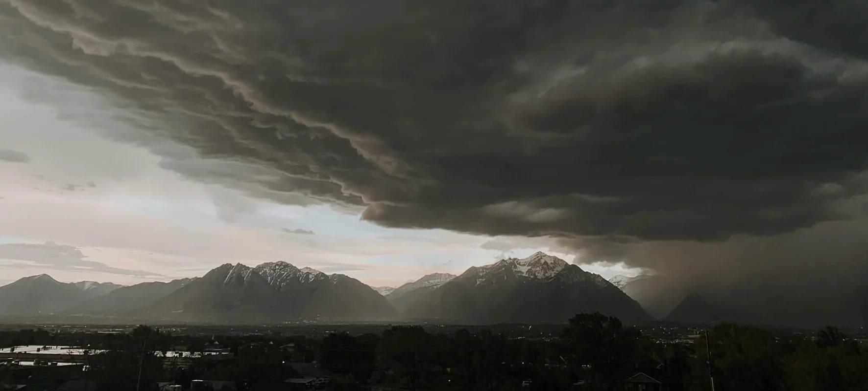 Dark storm clouds gathering above a mountain range and valley