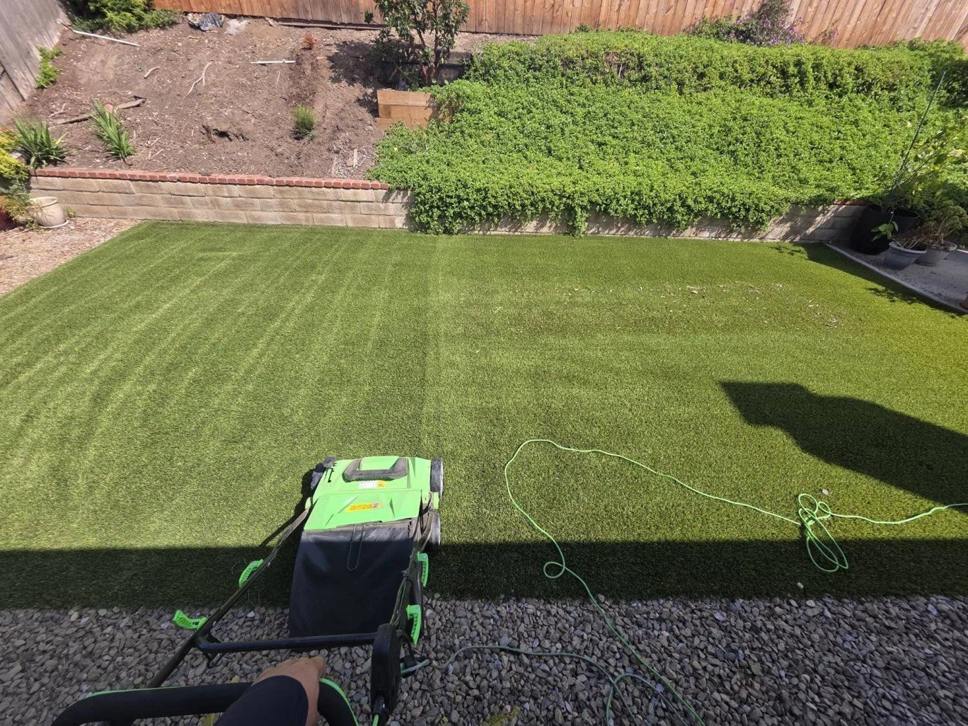 Hydroforce power-brushing a backyard of artificial turf, half groomed into fresh stripes