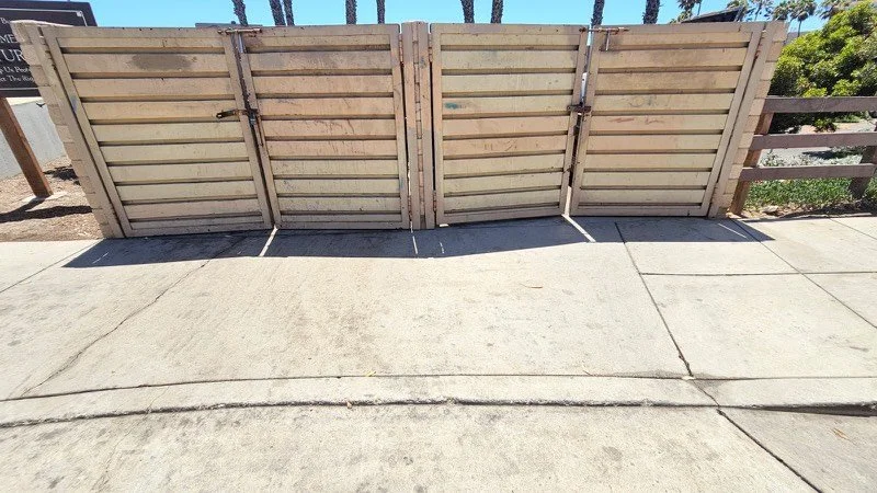 Same concrete walkway and gates after pressure washing, bright and clean