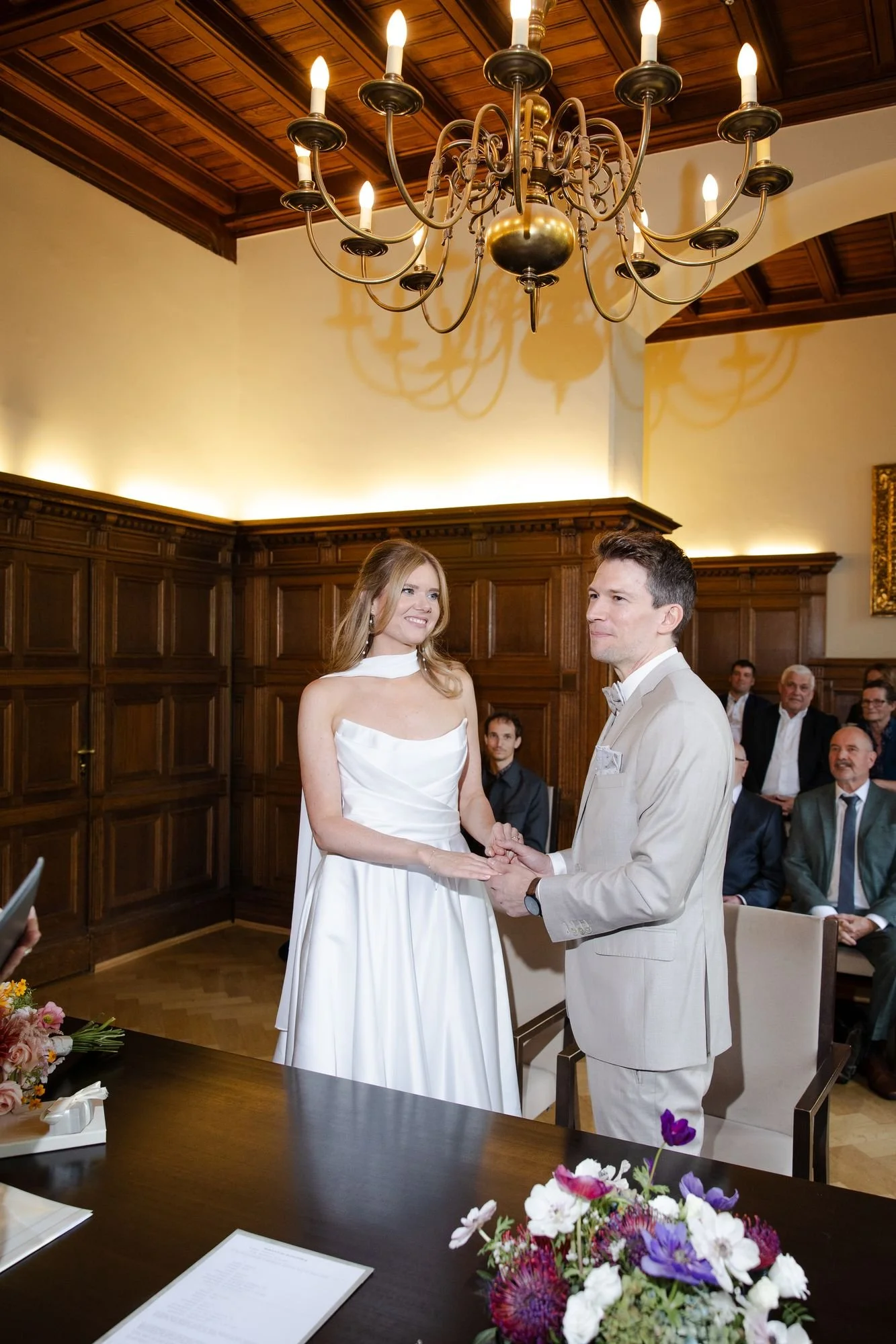 Civil wedding ceremony in a wood-panelled hall with chandelier