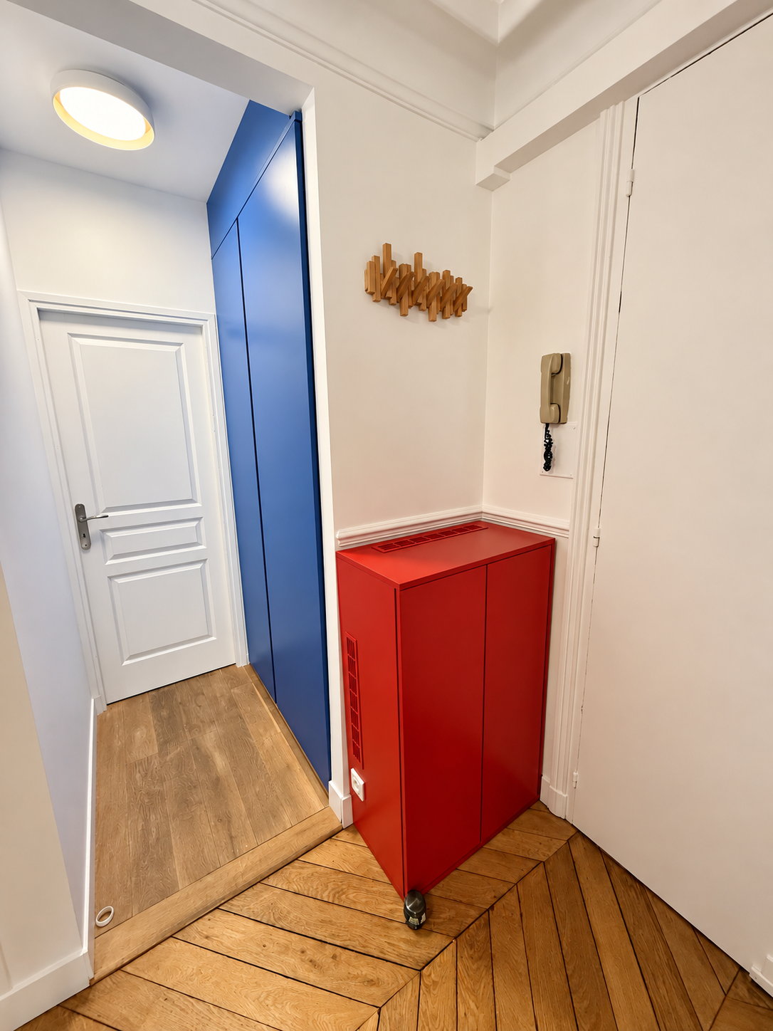 Meuble rouge et placard bleu dans l’entrée