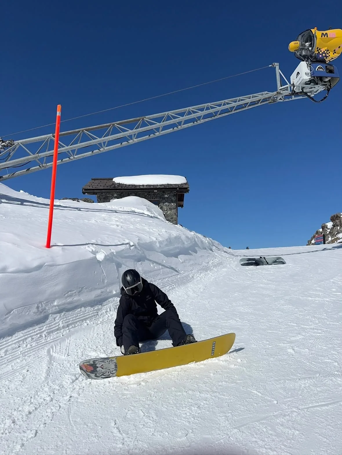 Snowboarder med TORAN skibrille sidder på gult snowboard under liften