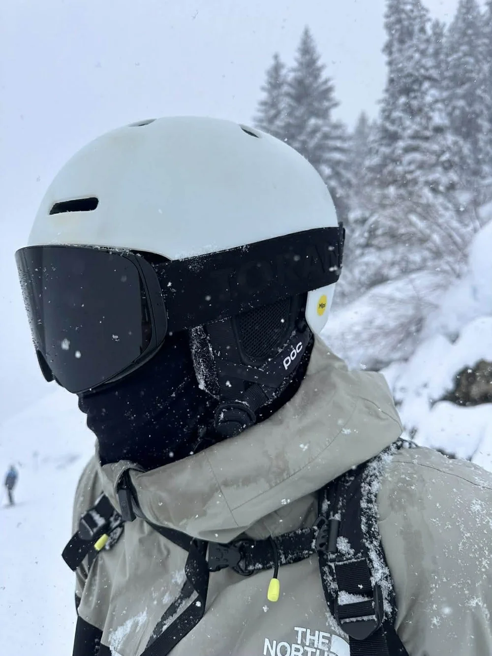 Nærbillede af mørk TORAN skibrille på hvid hjelm i snefald