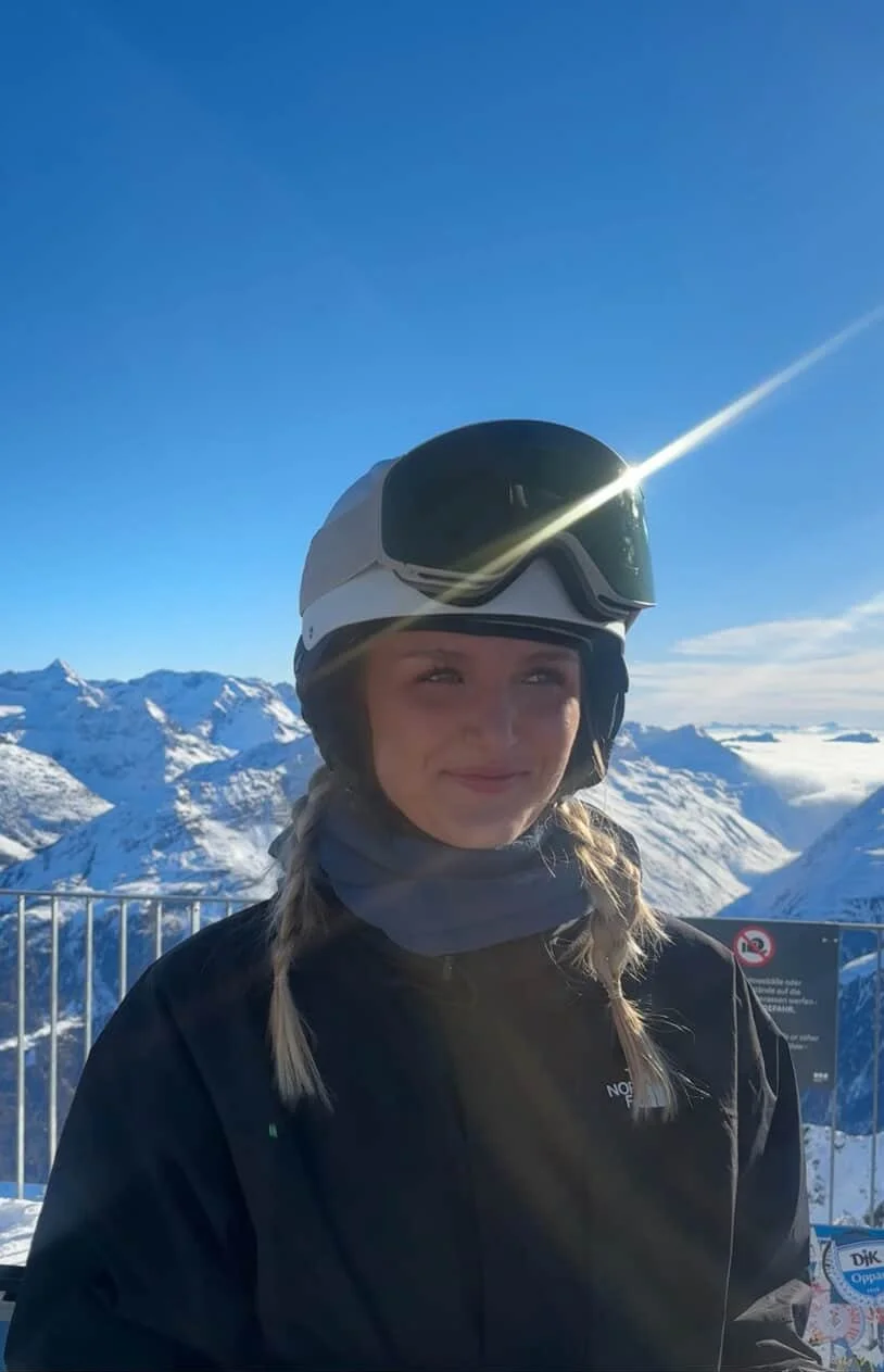 Kvinde med TORAN skibrille og grå hjelm foran blå himmel i højfjeld
