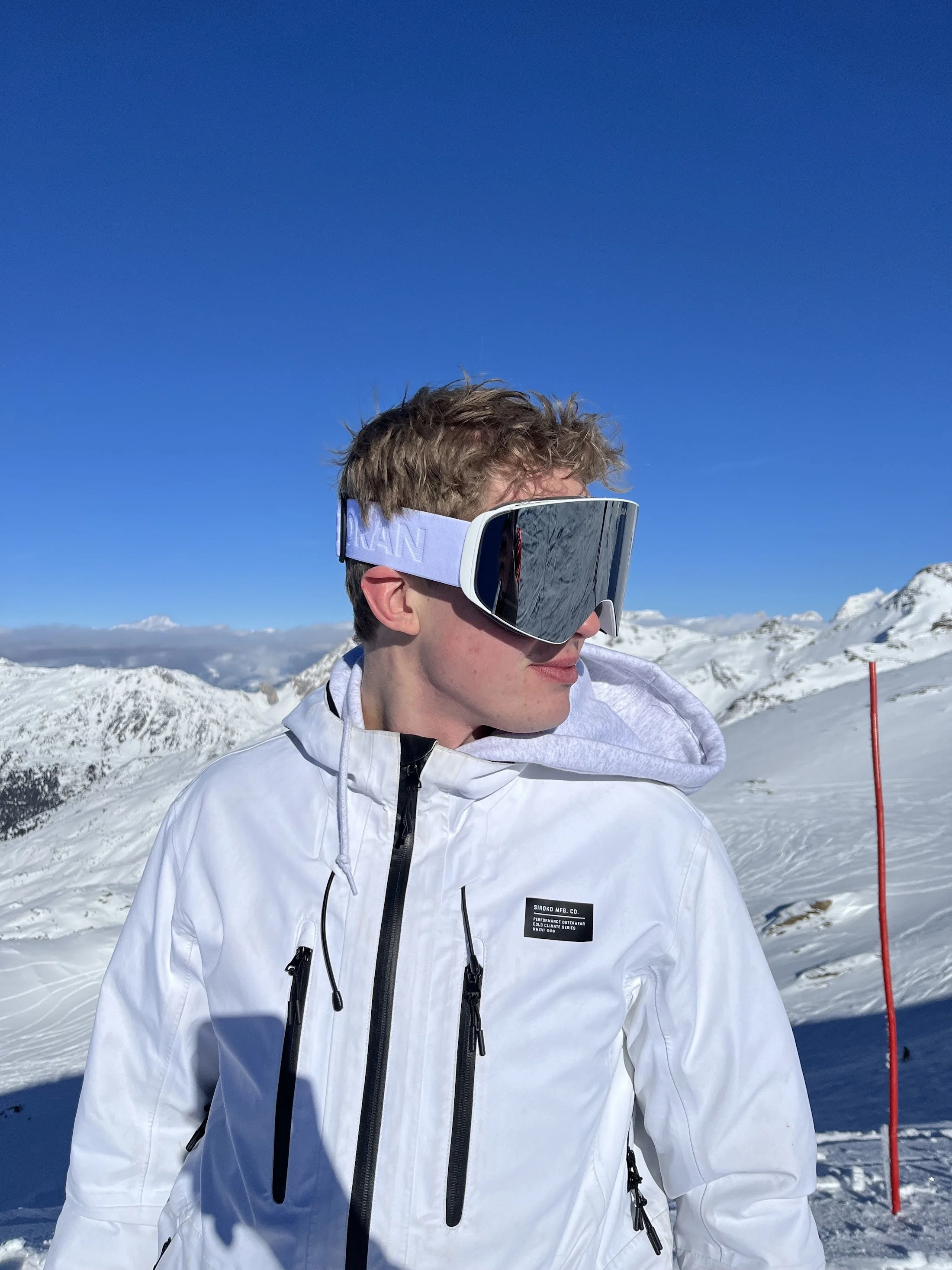 TORAN skibrille med spejlglas båret af skiløber i hvid jakke foran snedækkede alper i solskin