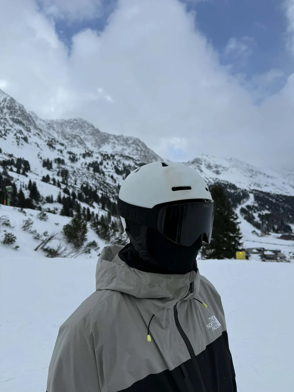 Skiløber med TORAN skibrille foran bjergpanorama i let skydække