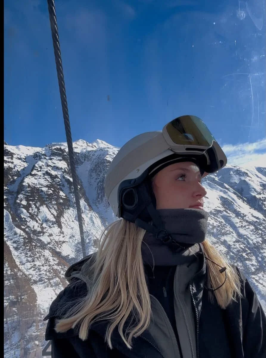 Kvinde i gondol med TORAN skibrille på hjelmen og udsigt til bjergtoppe