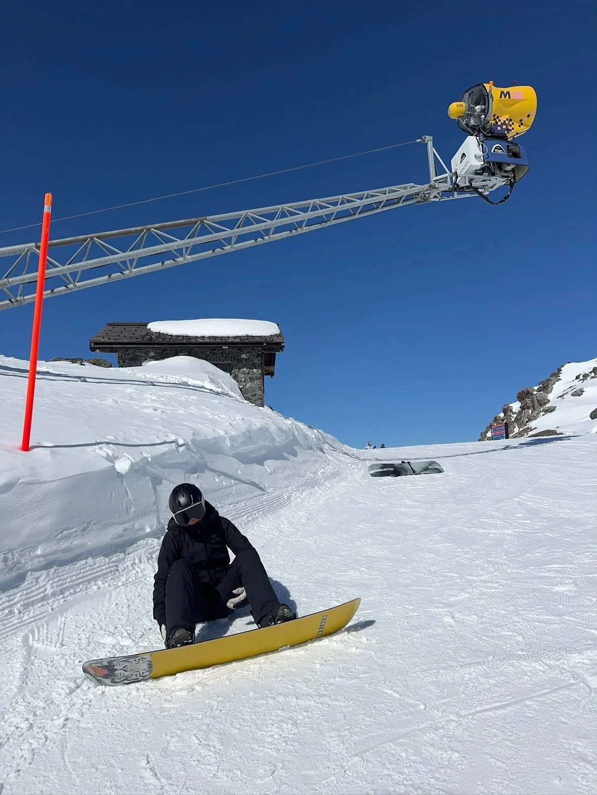 Snowboarder sidder i sneen med TORAN skibrille og gult board