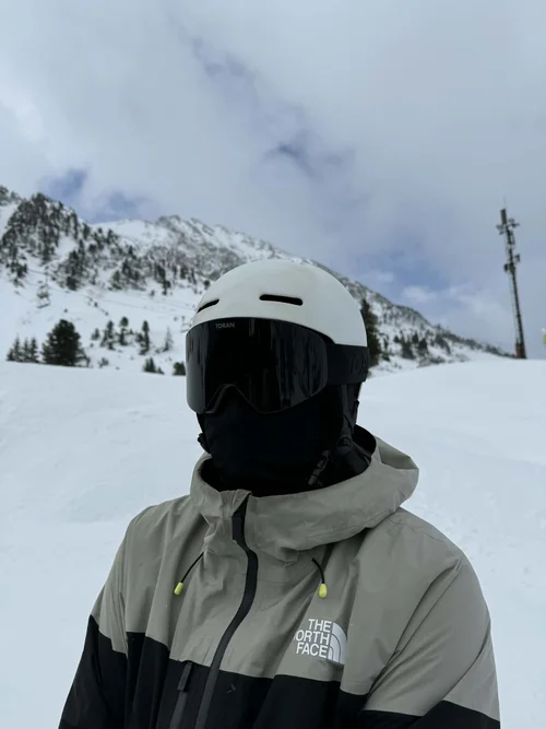 Skiløber med hvid hjelm og TORAN skibrille foran bjerge