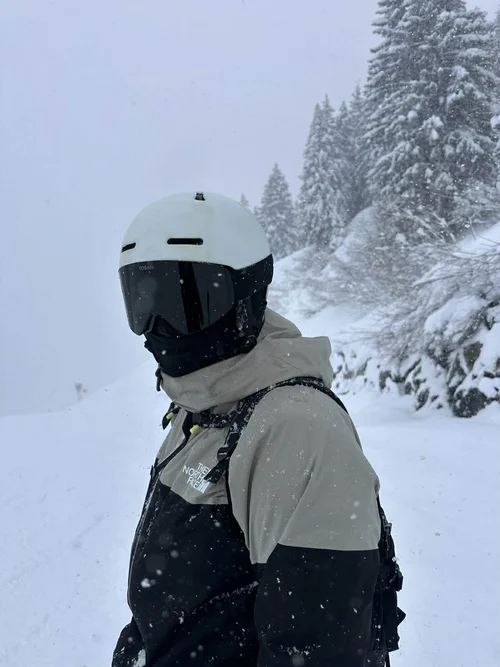 Skiløber med TORAN skibrille i sort jakke foran snedækket skov