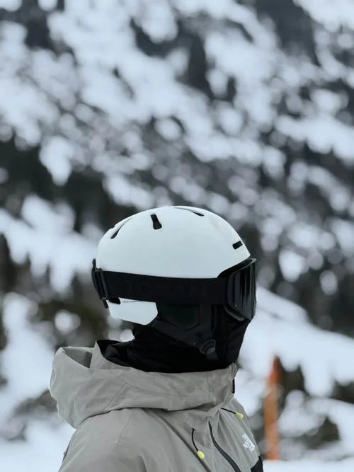 Skiløber med hvid hjelm og TORAN skibrille ved snedækket skov