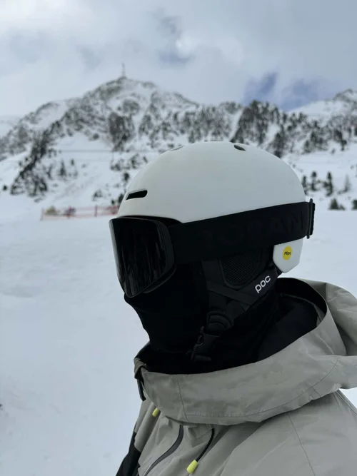 Skiløber med hvid hjelm og TORAN skibrille foran bjergtop
