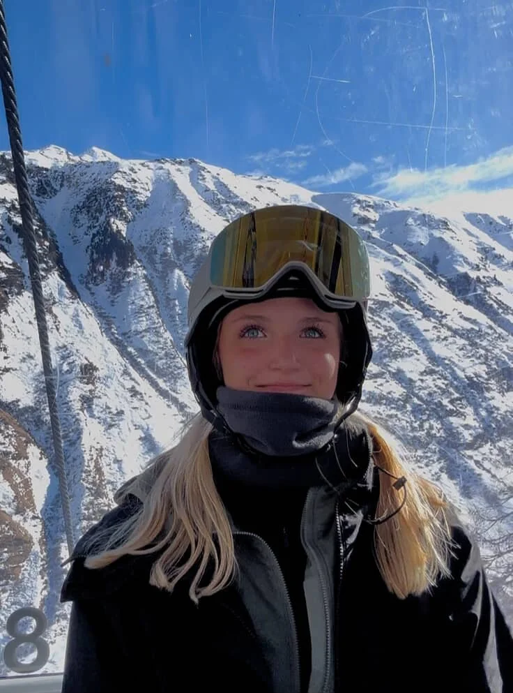 Kvinde med guld TORAN skibrille og sort hjelm foran solbeskinnede tinder