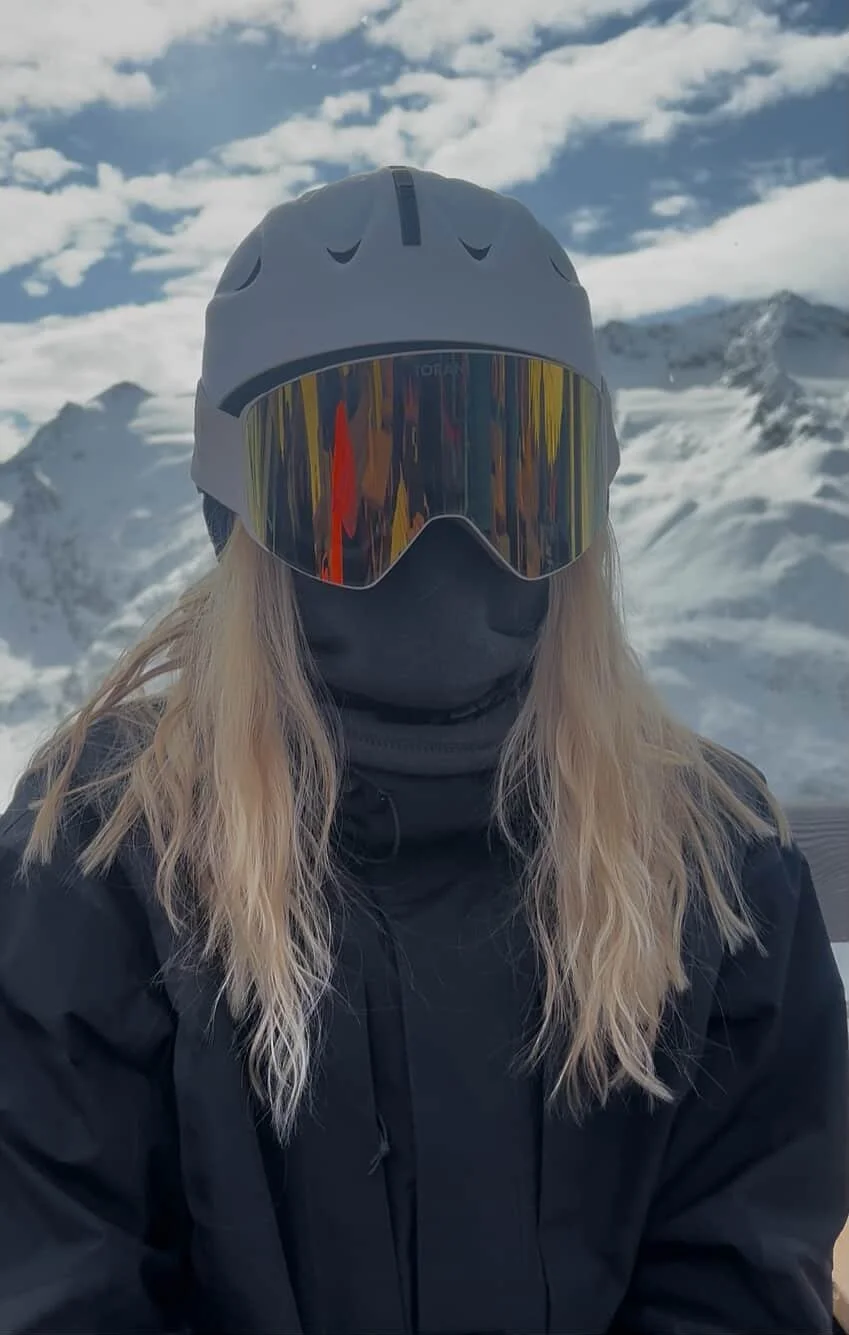 Portræt af kvinde med TORAN skibrille og grå hjelm under blå himmel