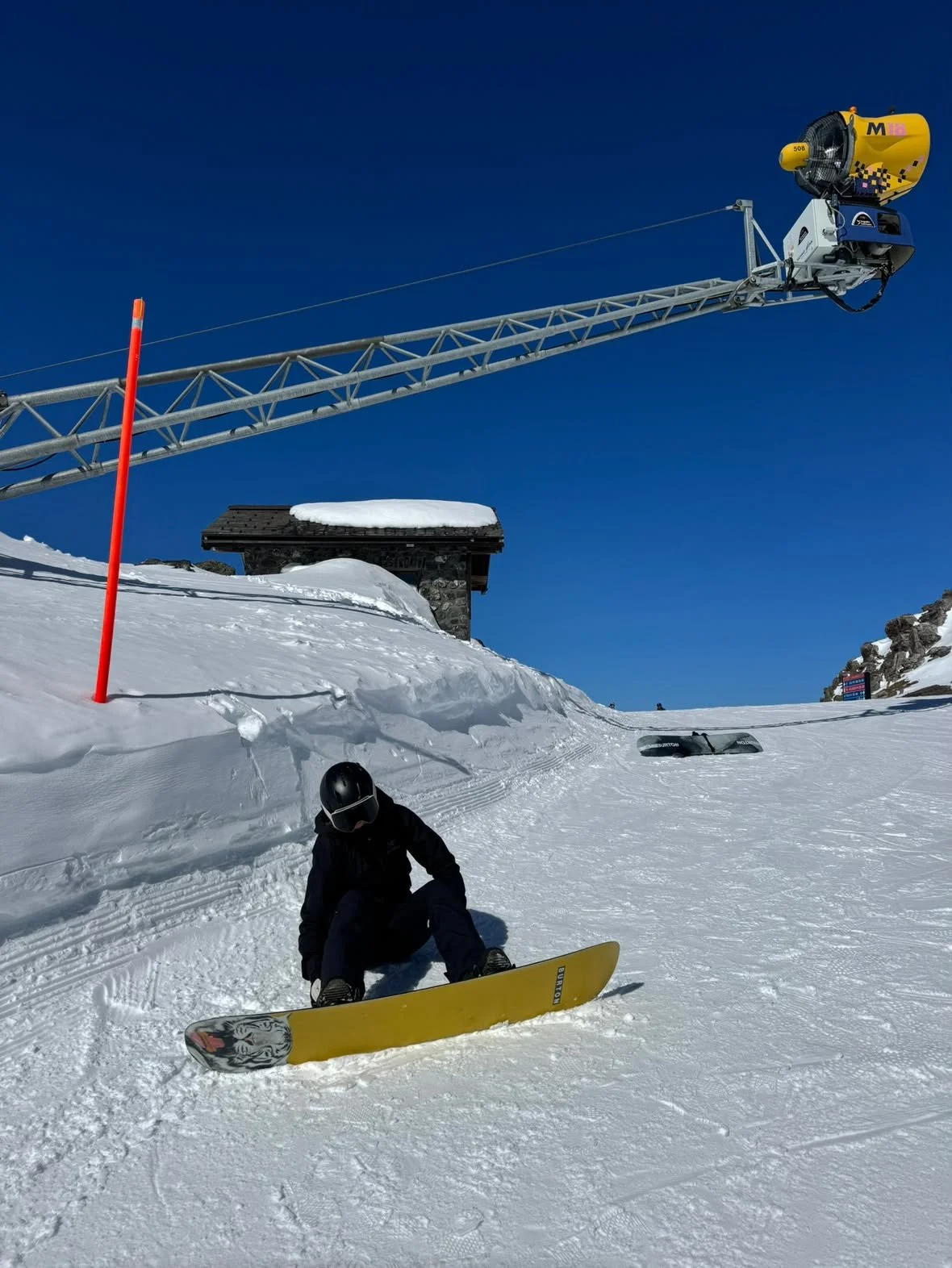 Snowboarder med TORAN skibrille sidder ved liftmasten i solskin