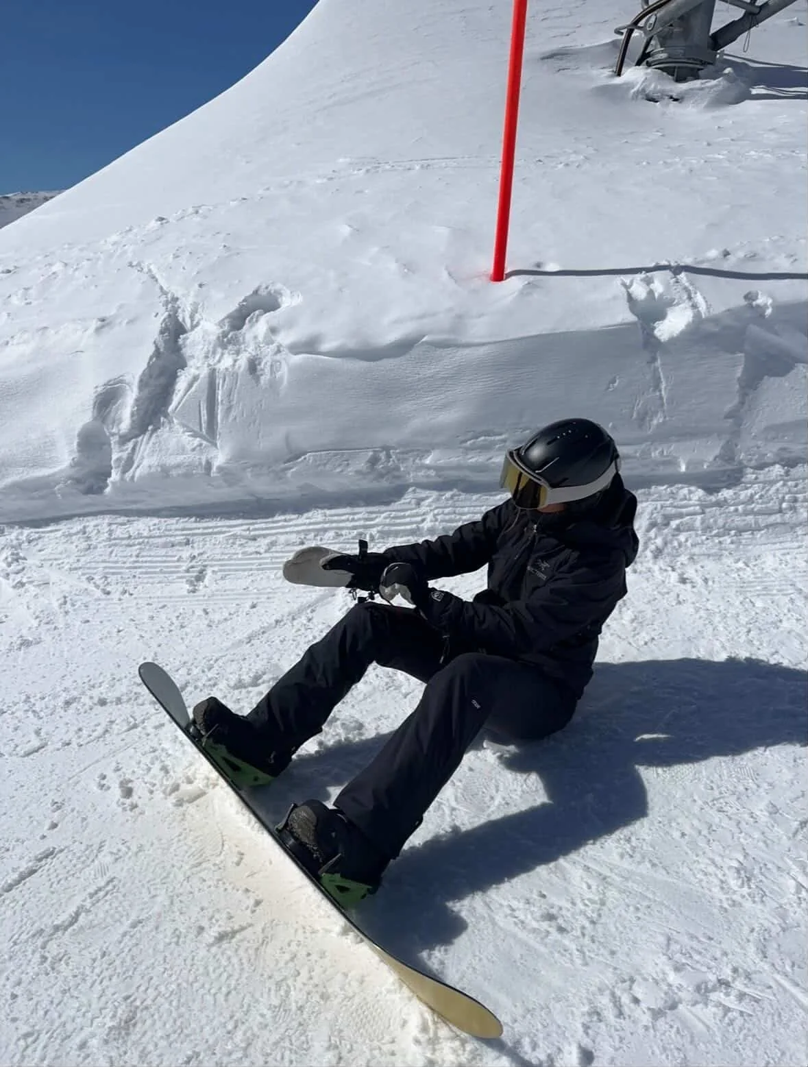 Snowboarder med TORAN skibrille sidder i sneen på pisten