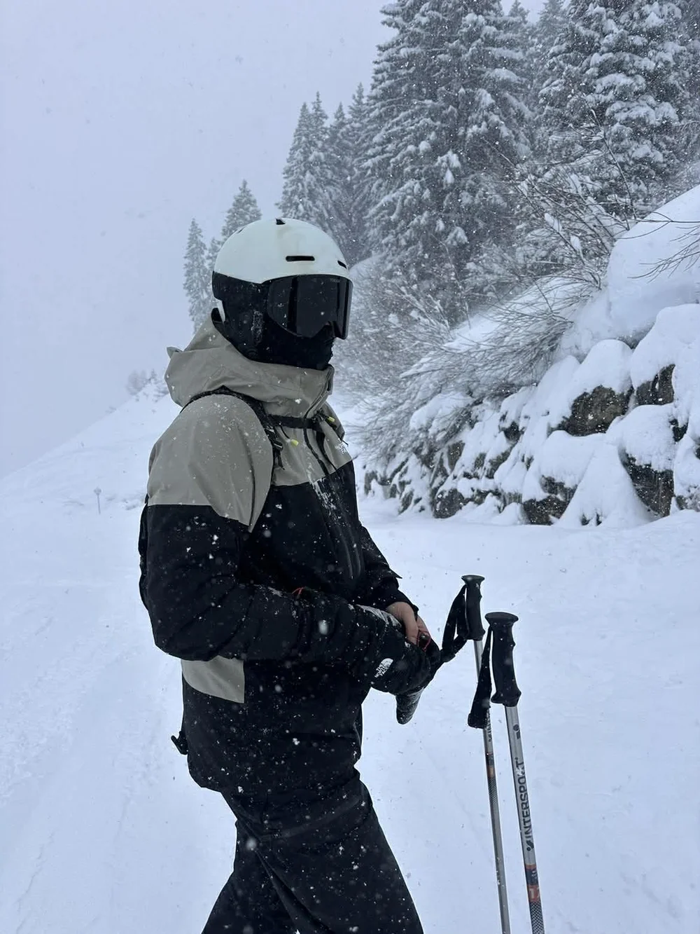 Skiløber står på pisten med TORAN skibrille mellem snedækkede graner