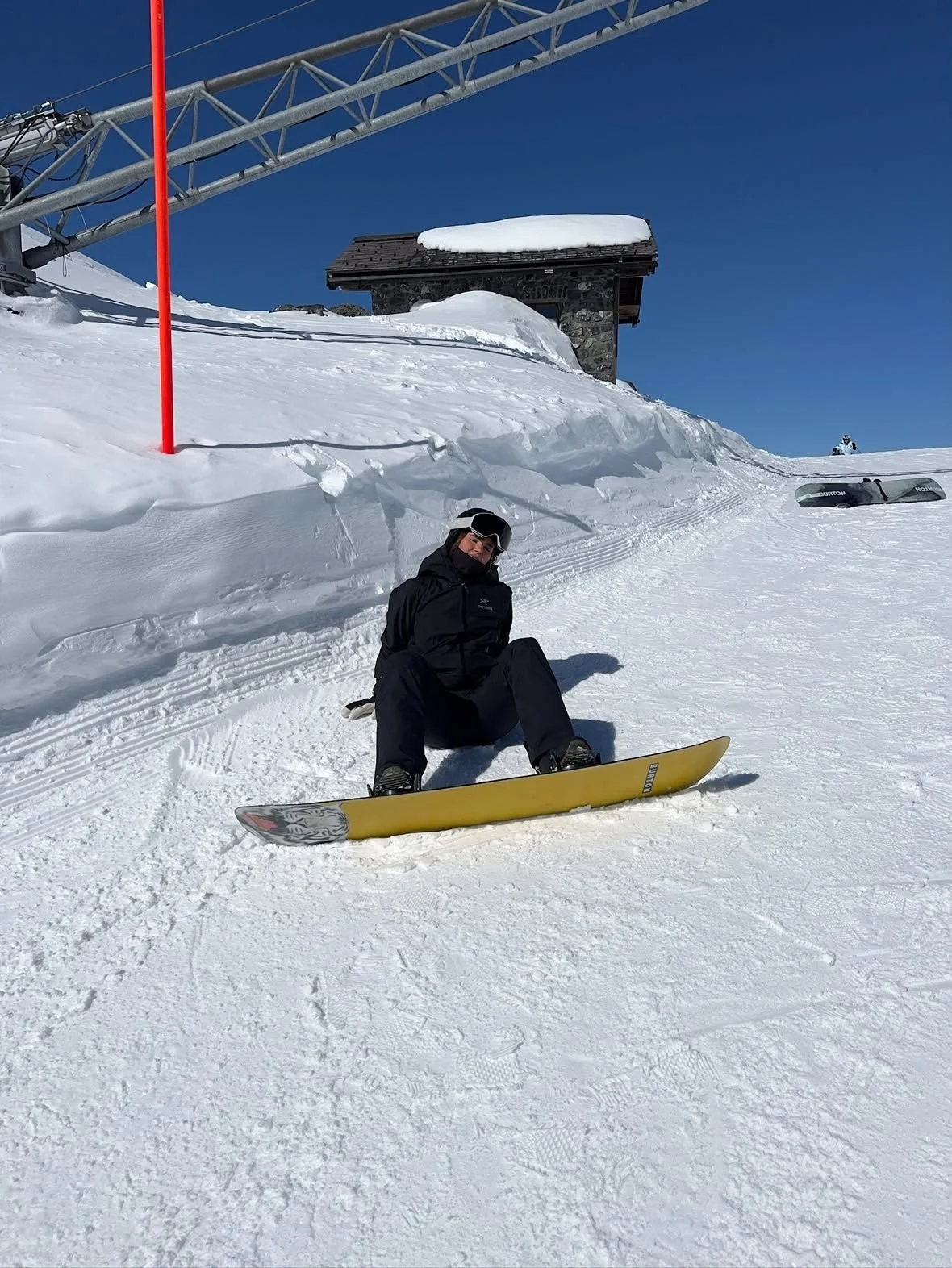 Snowboarder med TORAN skibrille sidder på gult board i sneen