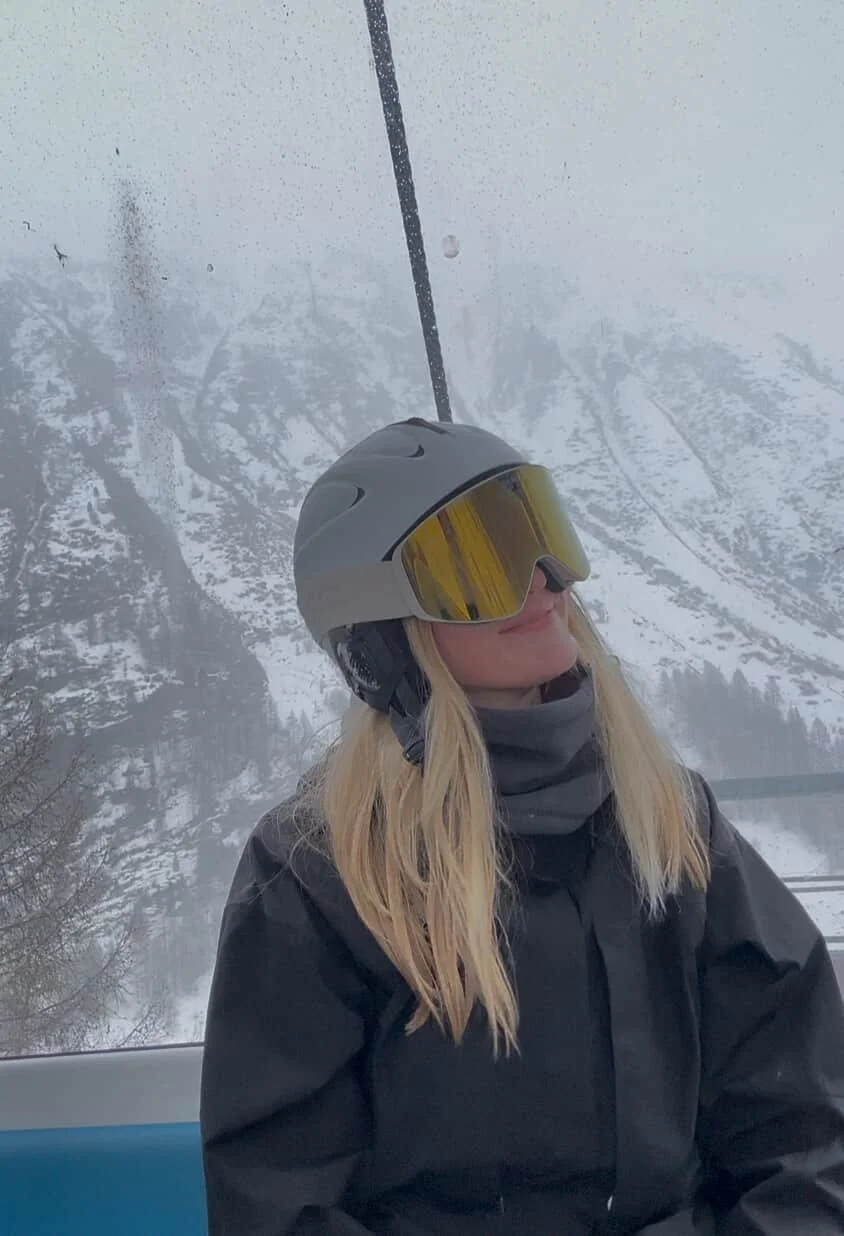Kvinde med TORAN skibrille i gondolen med snedækkede bjerge bagved