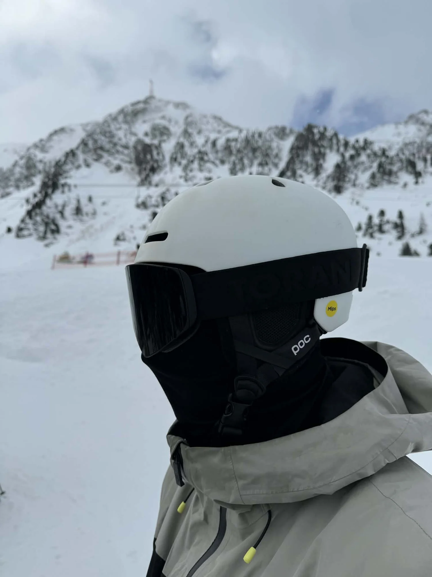Skiløber med hvid hjelm og sort TORAN skibrille foran sneklædte bjerge