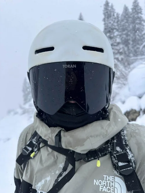 Nærbillede af hvid hjelm og TORAN skibrille med logo på stroppen