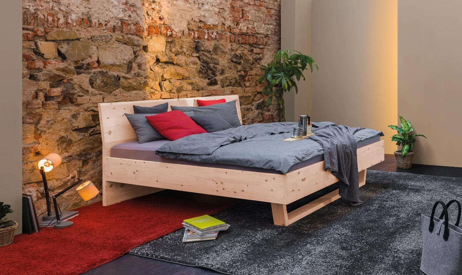 Dormiente Pinar bed in untreated Swiss pine against a stone wall
