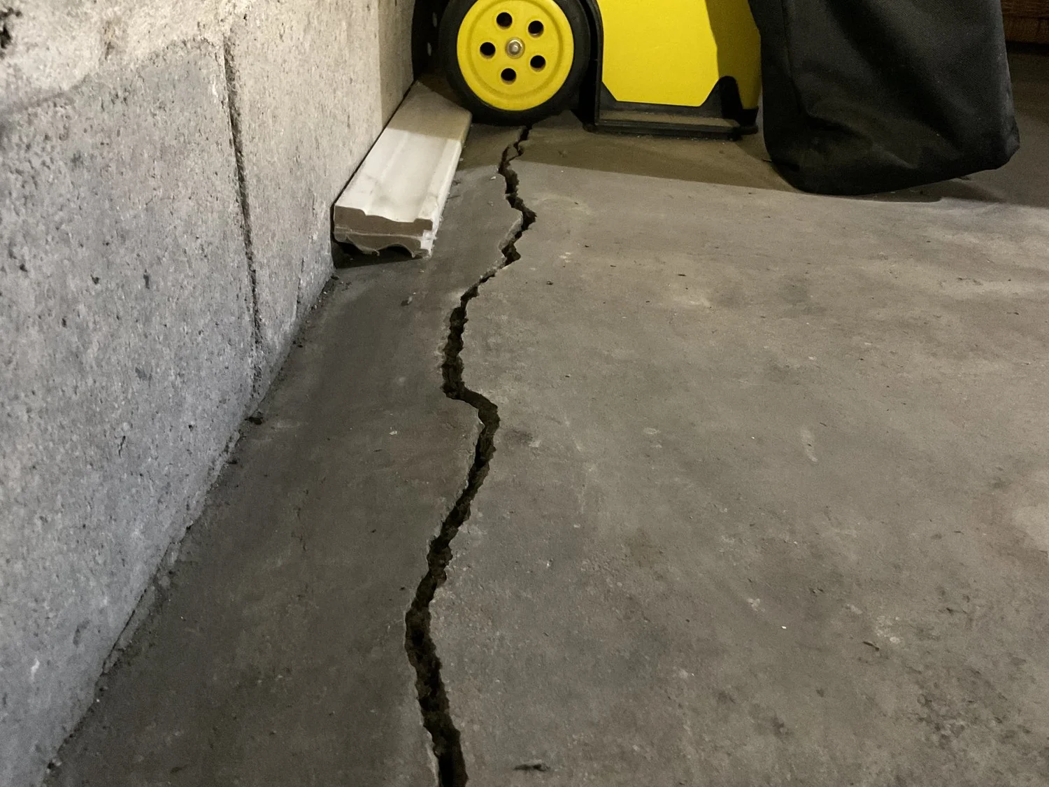 Slab crack with pitch running parallel with the foundation wall.