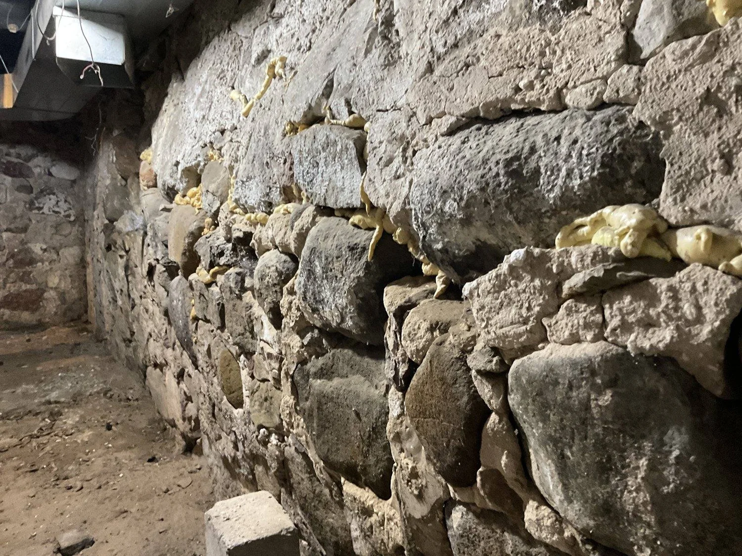 Rubble stone foundation with mortar washed out and stones loose at the face.