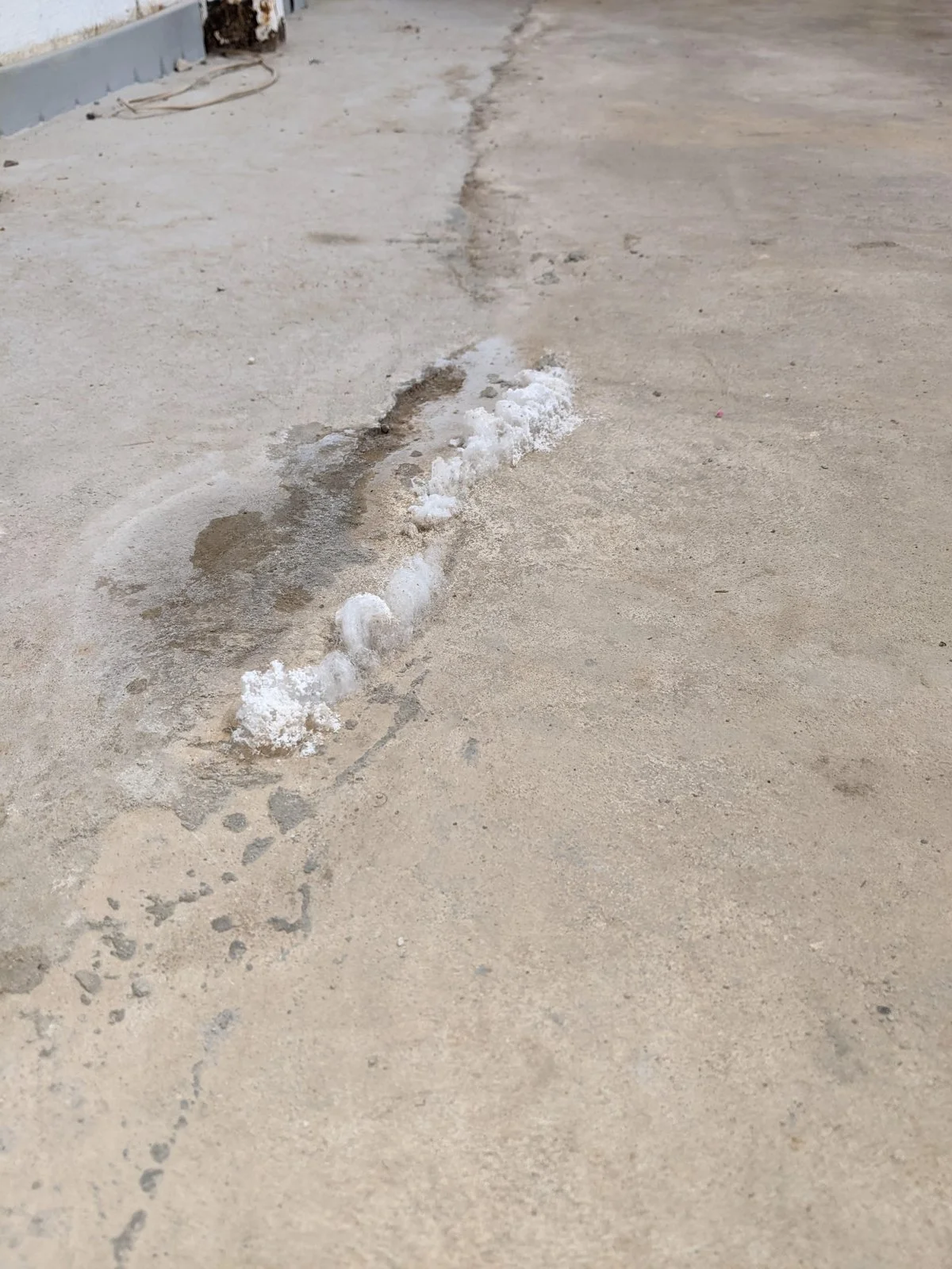 Slab crack with efflorescence and staining away from the wall