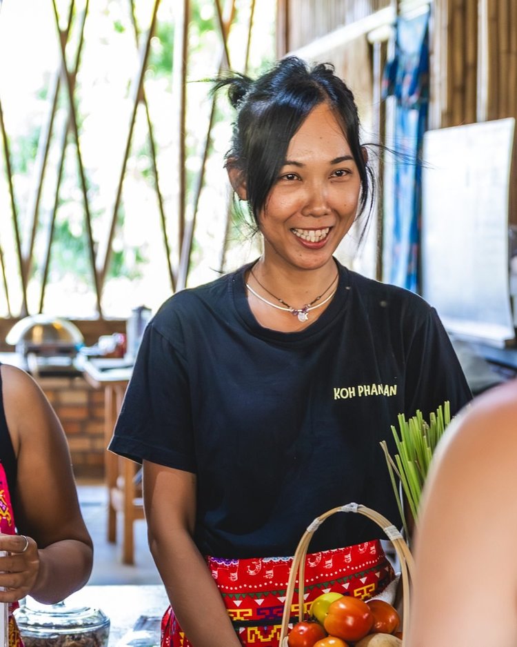 Thanita smiling behind fresh Thai ingredients at Proud Home