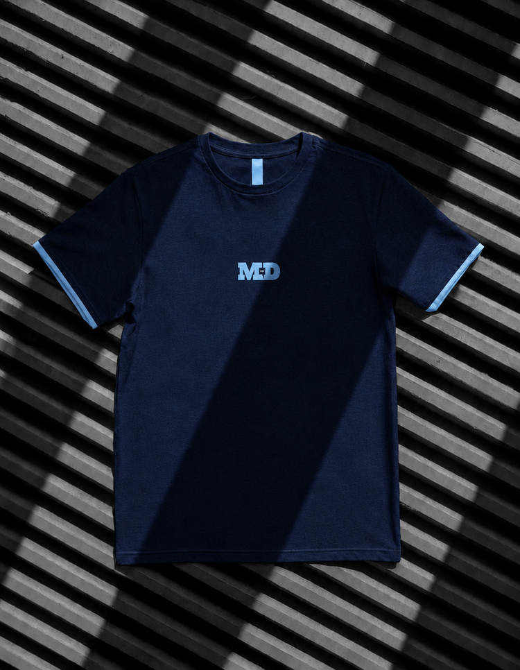 Navy training shirt with the MD monogram at the chest and sky blue cuff trim.