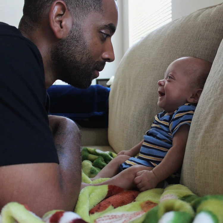 A father leaning close to his smiling baby