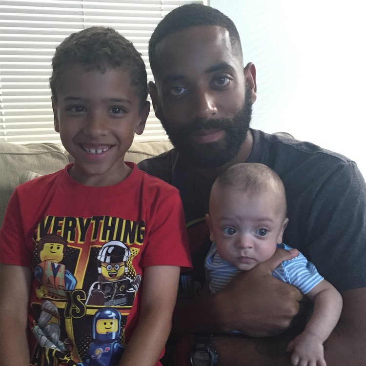 A father holding his baby beside his older son