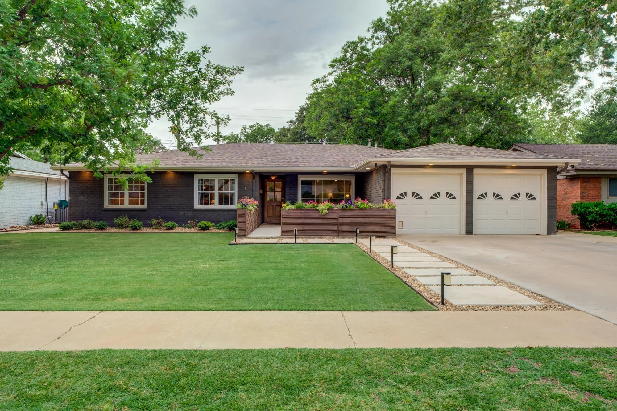 Updated dark-brick home with white trim, a landscaped lawn, and a welcoming front porch.