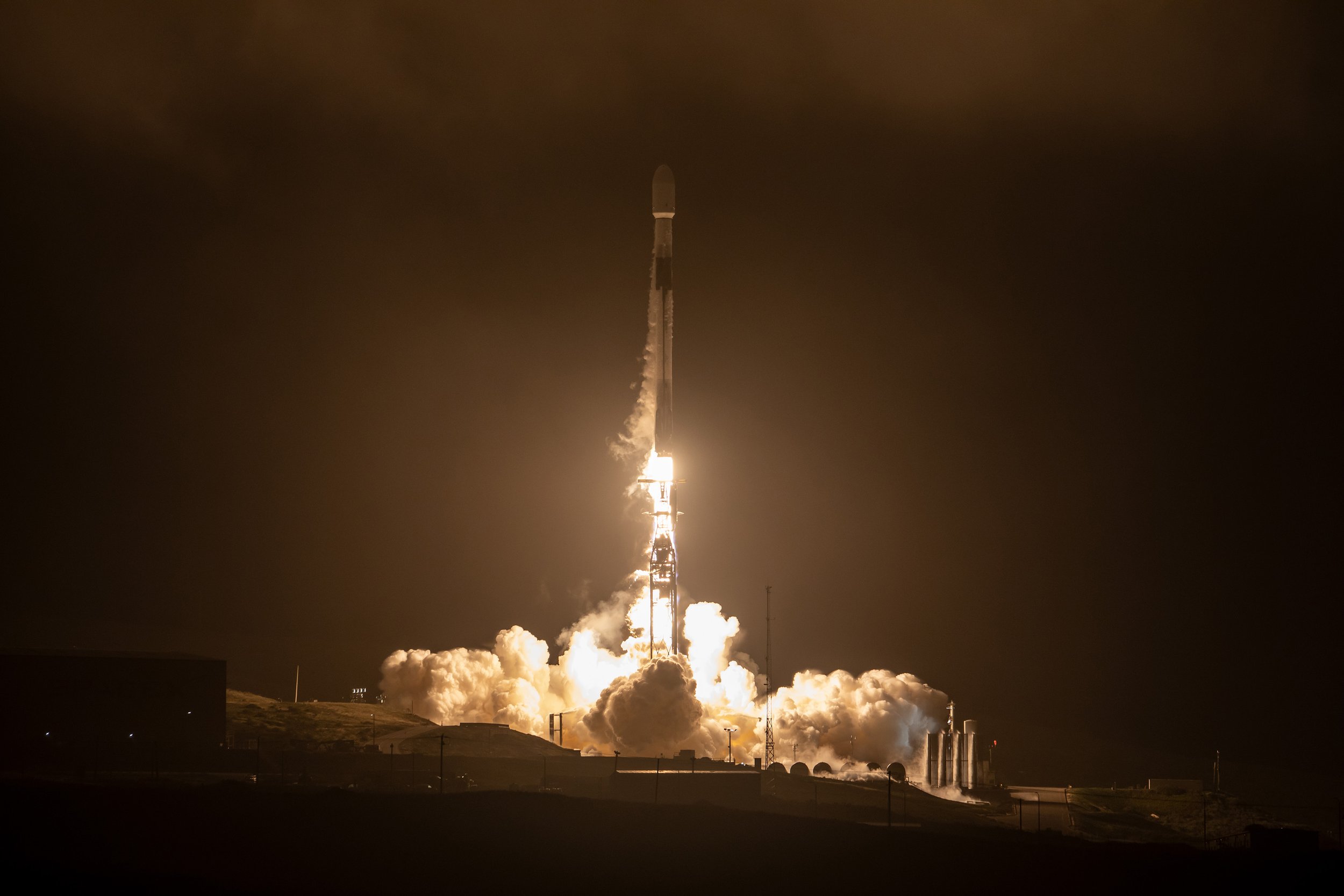 SpaceX Falcon 9 taking off at night in clouds illuminated by rocket exhaust