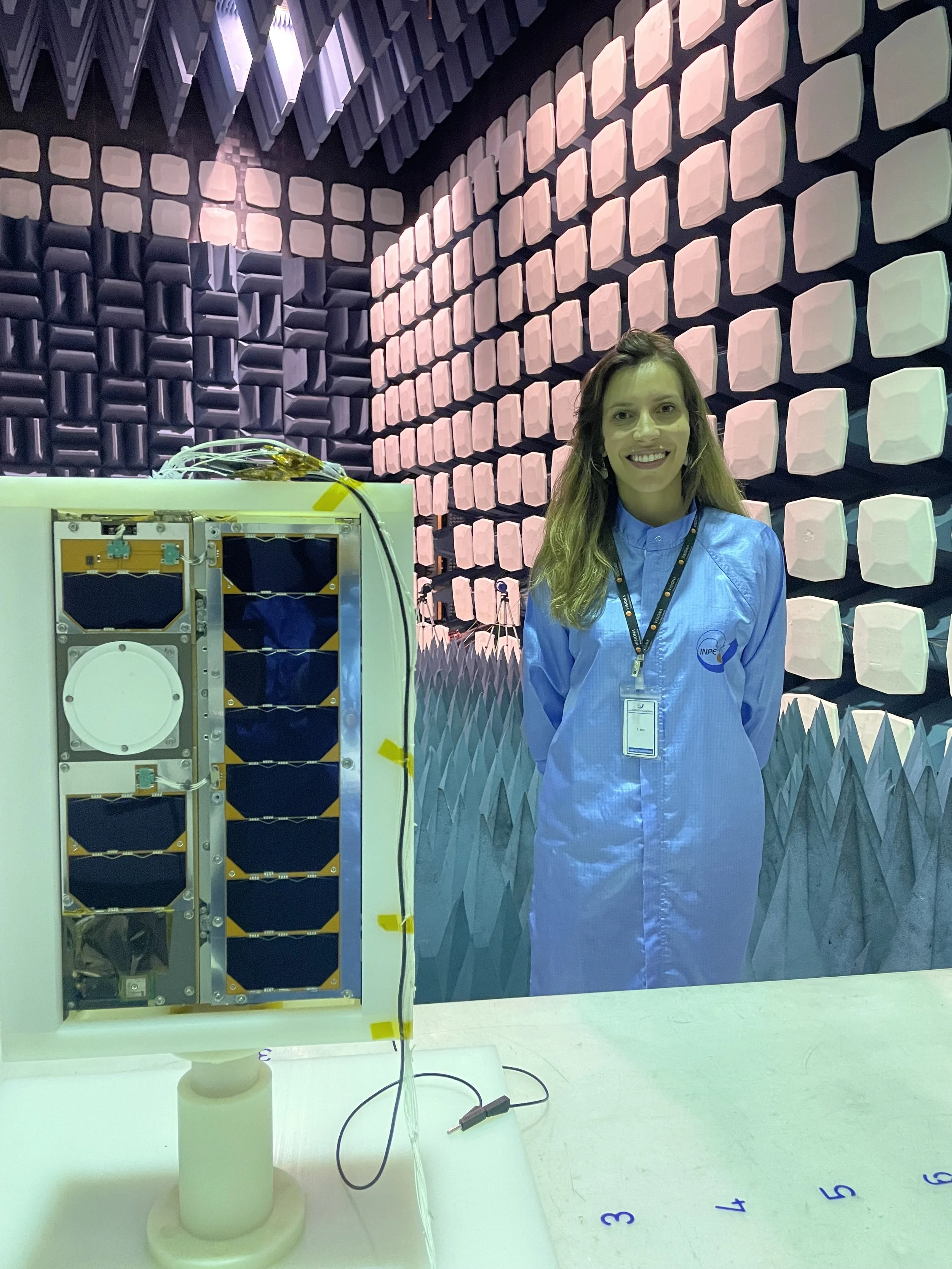 Mariana Barbosa beside the VCUB1 satellite inside an acoustic testing chamber