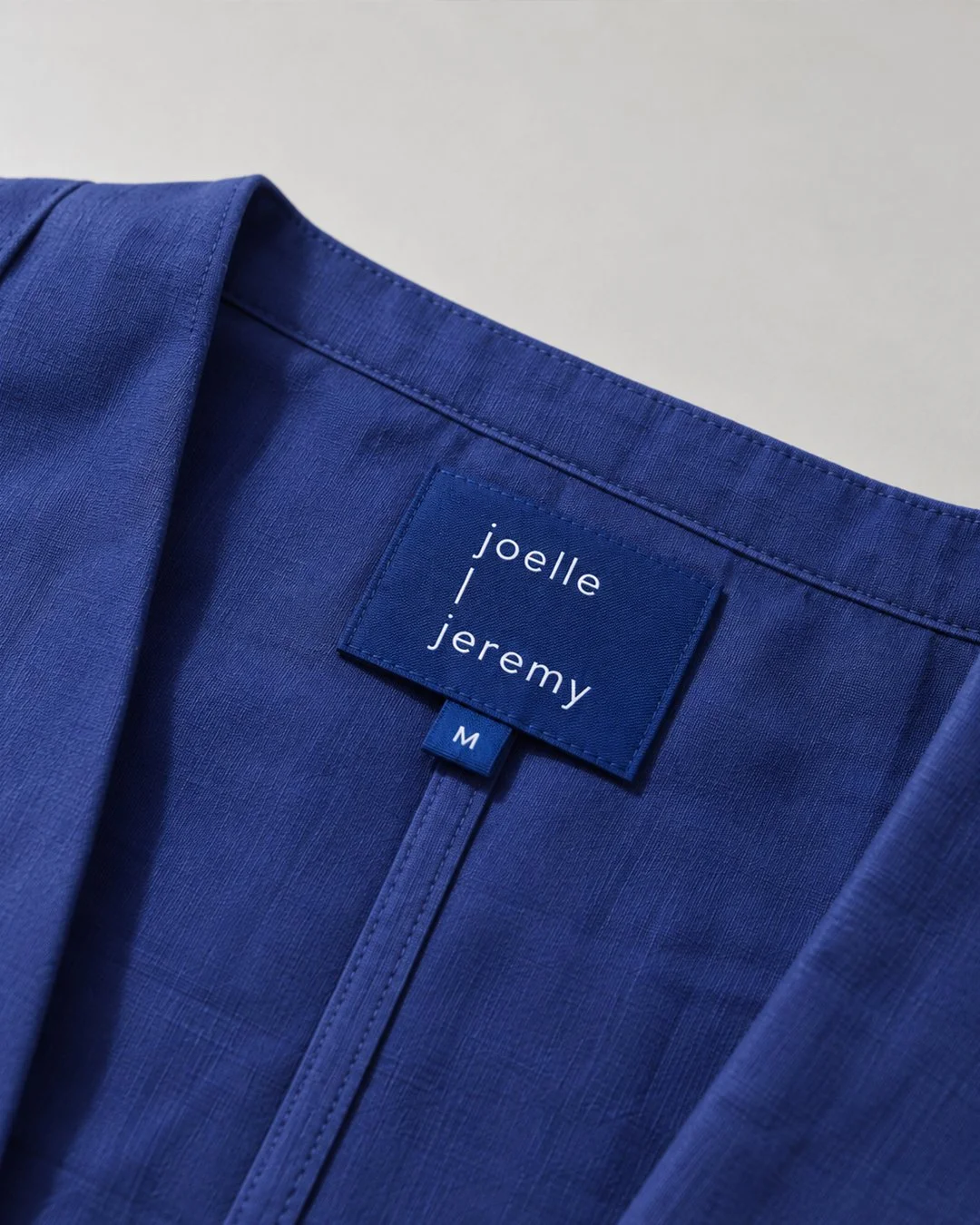 Détail d’un kimono bleu et de son étiquette Joelle & Jeremy.