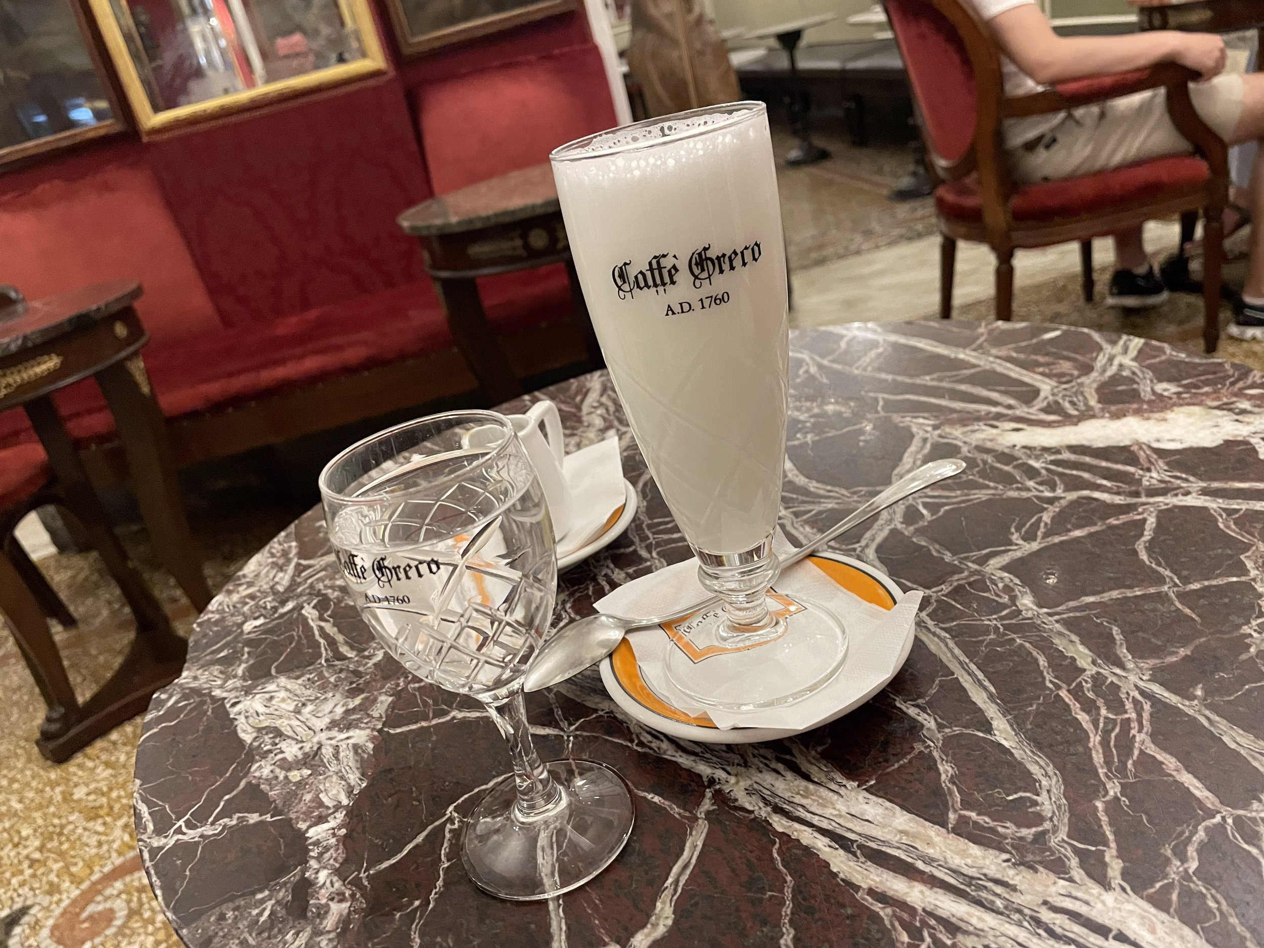 A Caffè Greco dessert drink on a marble table.