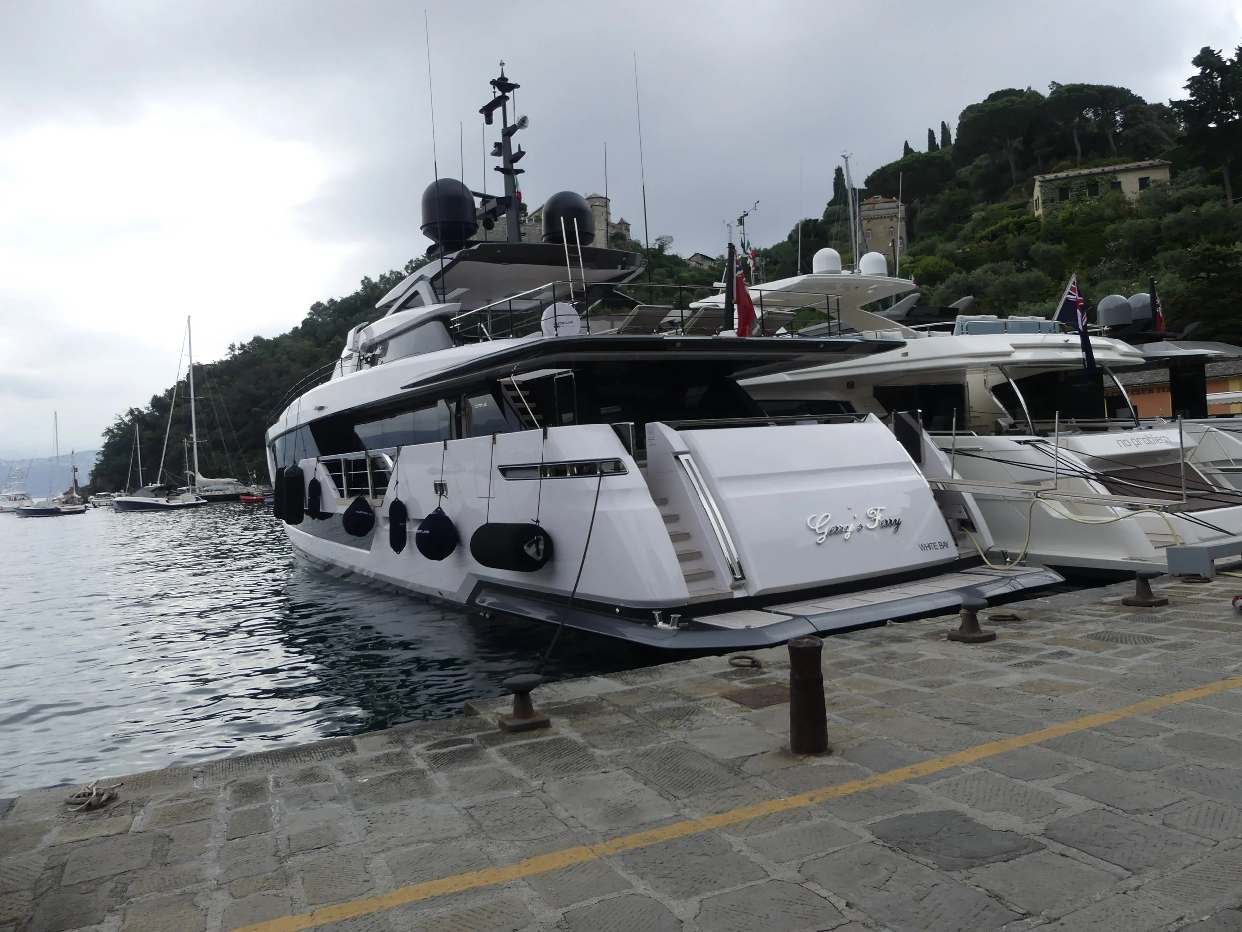 A white yacht in Portofino's marina, green hills behind.