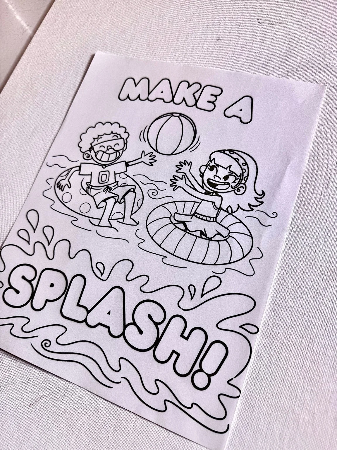 A printed Make a Splash coloring page with illustrated children, float rings and a beach ball.