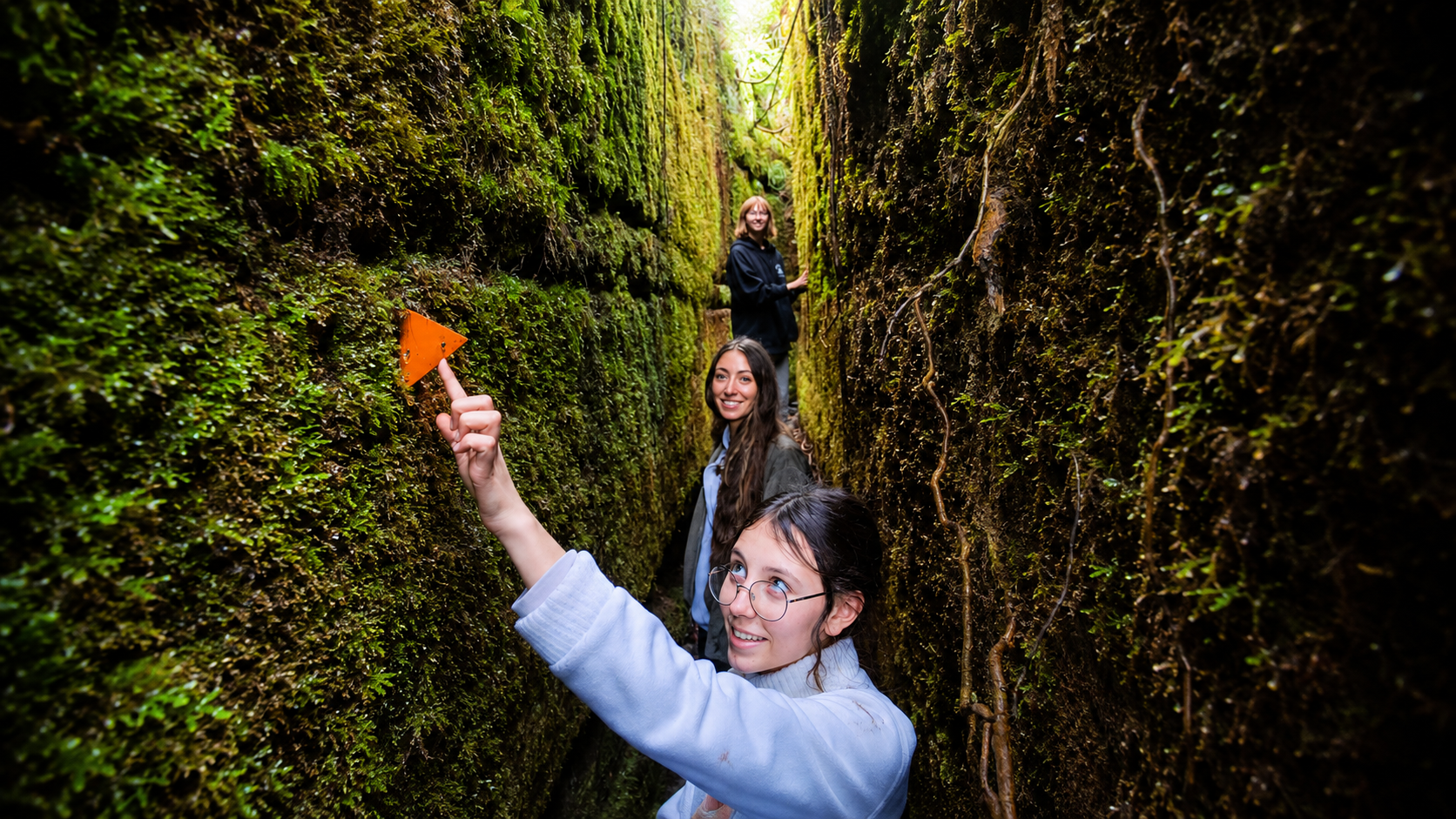 Family standing inside the narrow moss-covered water race on Blue Spur Bushwalk near Hokitika